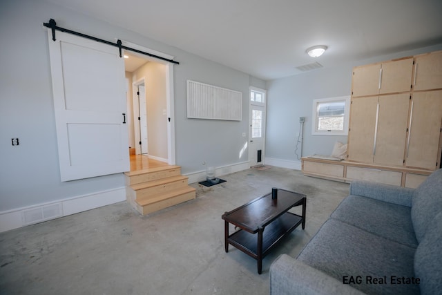 living room with a barn door, unfinished concrete floors, baseboards, and visible vents