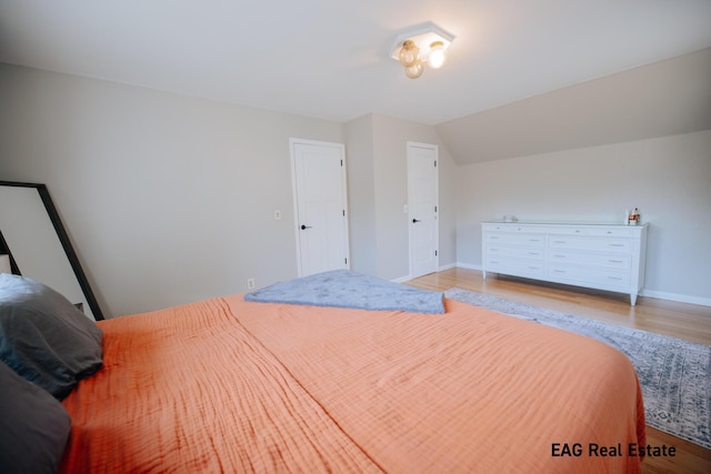 bedroom with lofted ceiling, wood finished floors, and baseboards