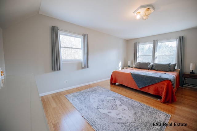 bedroom with vaulted ceiling, baseboards, and wood finished floors