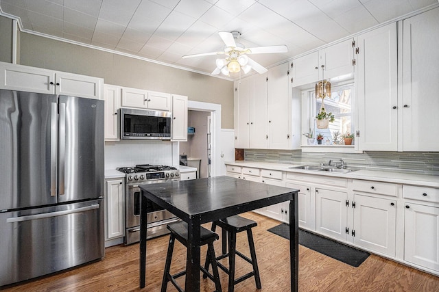 kitchen with backsplash, wood finished floors, appliances with stainless steel finishes, and a sink