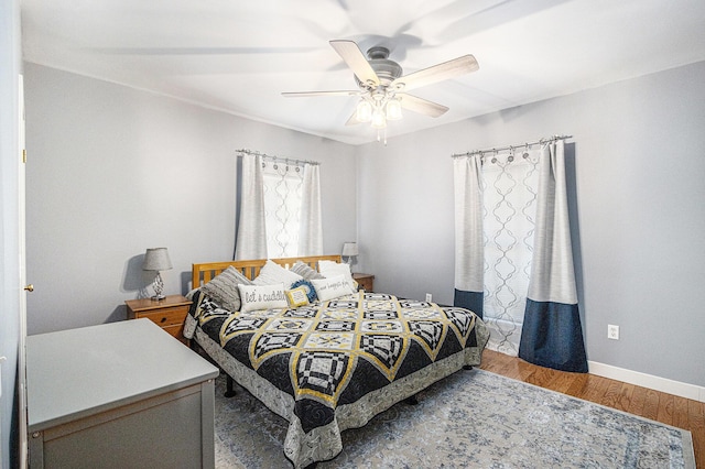 bedroom featuring baseboards, wood finished floors, and a ceiling fan