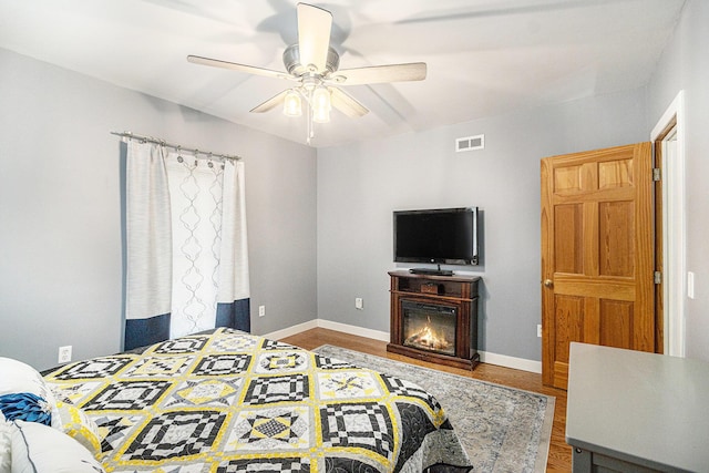 bedroom with visible vents, ceiling fan, baseboards, and wood finished floors