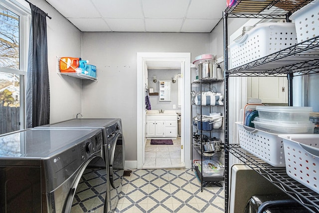 clothes washing area with laundry area, washing machine and dryer, baseboards, and light floors