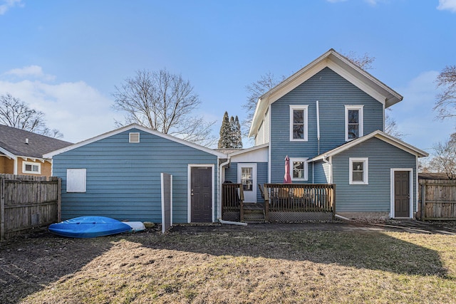 rear view of house featuring a deck and fence