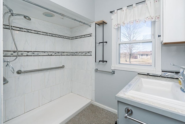 full bathroom with vanity, baseboards, and a tile shower