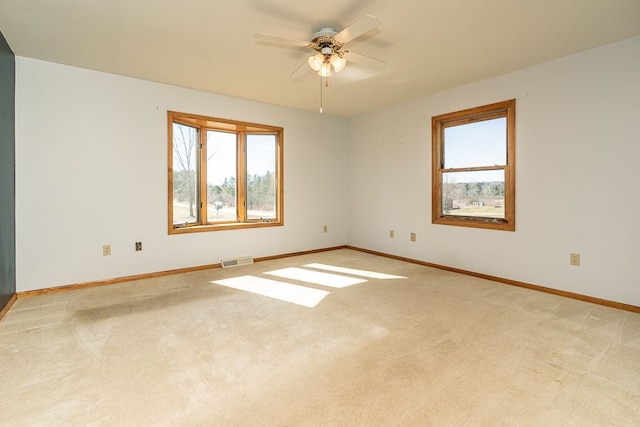 carpeted spare room with visible vents, a ceiling fan, and baseboards