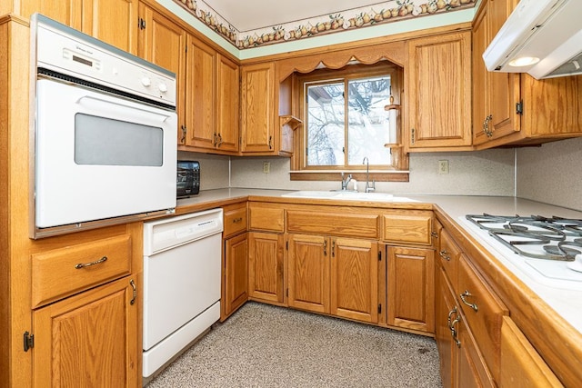 kitchen with brown cabinets, white appliances, light countertops, and extractor fan