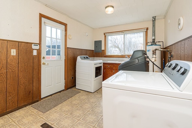 laundry area featuring laundry area, separate washer and dryer, water heater, wood walls, and wainscoting