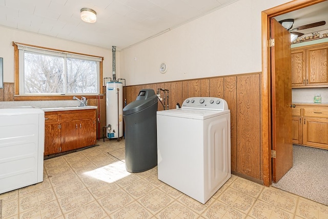 laundry area featuring washing machine and clothes dryer, light floors, water heater, wainscoting, and cabinet space