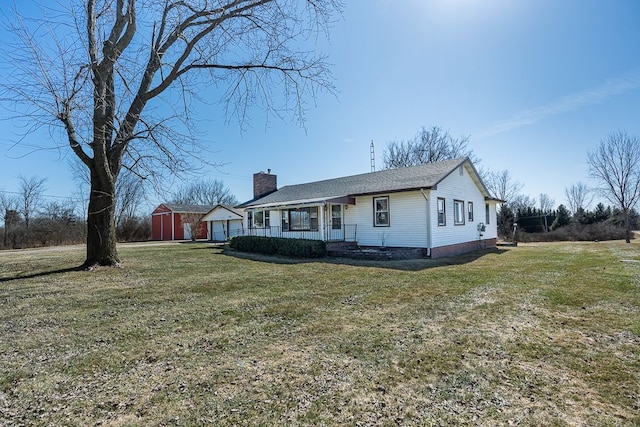 view of front facade featuring an outdoor structure, a garage, a front yard, and a chimney