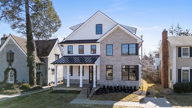 modern farmhouse with a standing seam roof, a front lawn, covered porch, and metal roof