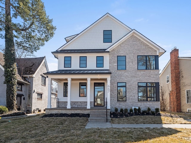 view of front of home with a front yard, covered porch, metal roof, stone siding, and a standing seam roof