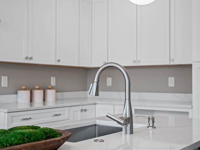interior details featuring light stone counters, white cabinetry, and a sink