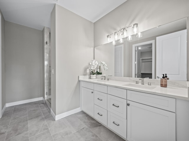 full bathroom featuring double vanity, a shower stall, baseboards, and a sink