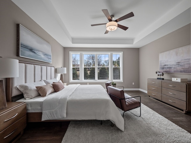 bedroom featuring baseboards, a ceiling fan, dark wood-style floors, and a raised ceiling
