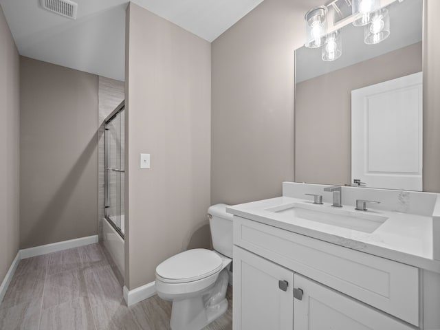 bathroom featuring visible vents, toilet, vanity, baseboards, and bath / shower combo with glass door