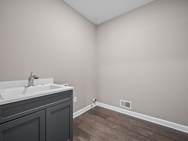 clothes washing area with dark wood-style floors, a sink, baseboards, visible vents, and cabinet space