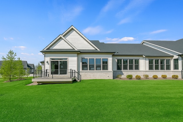 rear view of house featuring brick siding, a yard, and a deck