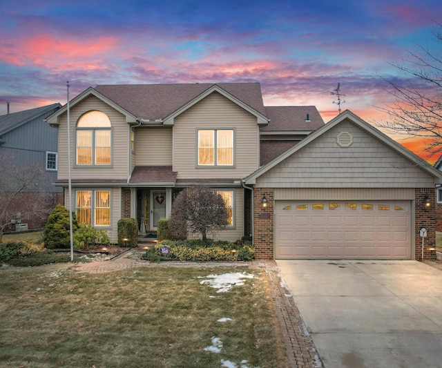 traditional-style home featuring roof with shingles, driveway, a garage, a lawn, and brick siding