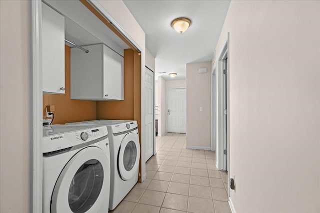 laundry room with light tile patterned floors, cabinet space, baseboards, and washer and clothes dryer