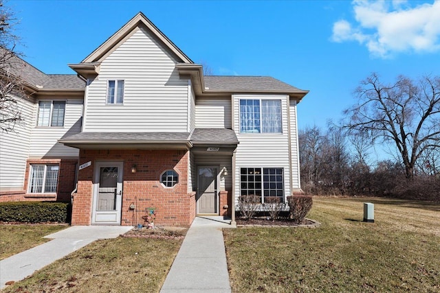 townhome / multi-family property with brick siding, a shingled roof, and a front lawn