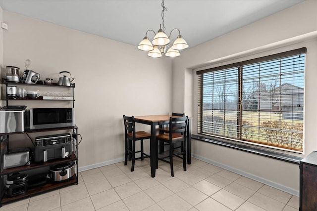 dining area featuring a chandelier, baseboards, and light tile patterned flooring