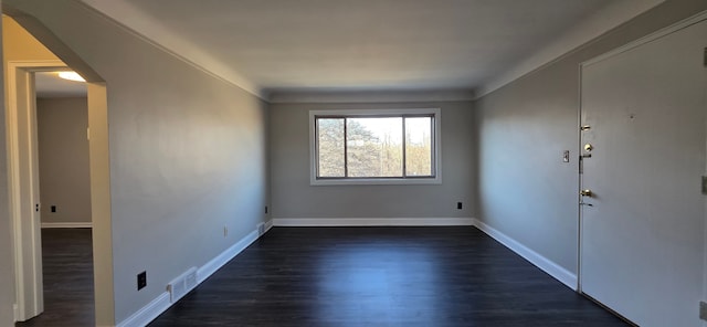 empty room featuring visible vents, baseboards, and dark wood-type flooring