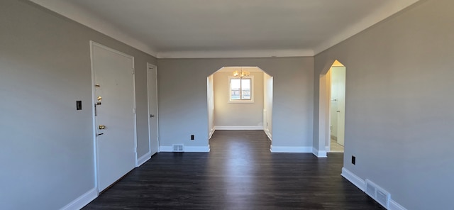 empty room featuring arched walkways, dark wood-style floors, baseboards, and visible vents