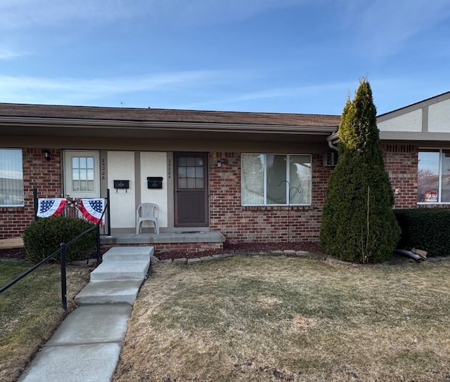 view of front of house with brick siding, covered porch, and a front yard