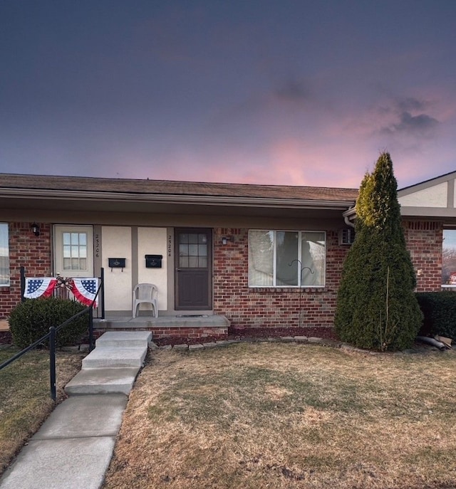 view of front of house with brick siding, a porch, a front lawn, and fence