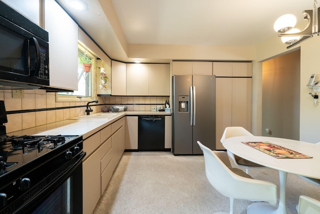 kitchen featuring backsplash, black appliances, light countertops, and a sink