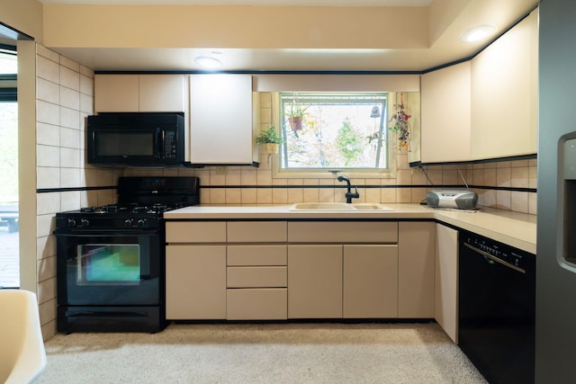 kitchen with a sink, black appliances, light countertops, white cabinetry, and tasteful backsplash