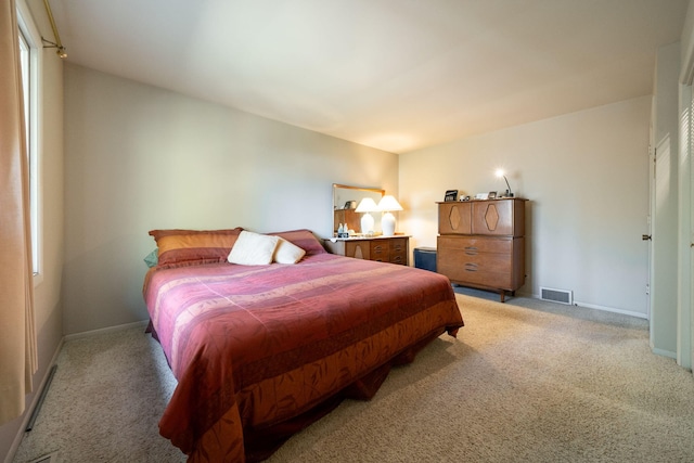 bedroom featuring visible vents, light carpet, and baseboards