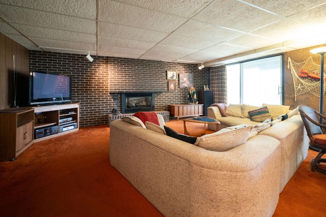 carpeted living room featuring a brick fireplace and brick wall