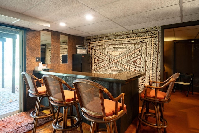 bar featuring a drop ceiling, a dry bar, and freestanding refrigerator