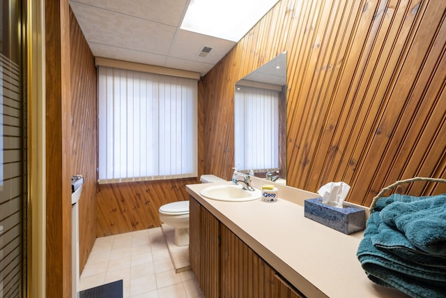 bathroom featuring visible vents, a drop ceiling, wood walls, toilet, and vanity