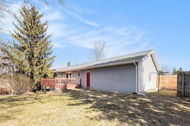 rear view of property with a yard, a deck, and fence