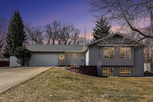 tri-level home featuring concrete driveway, an attached garage, and a lawn