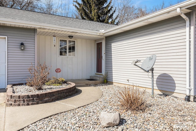 entrance to property featuring a shingled roof and a garage