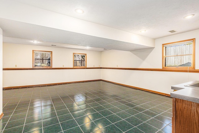 interior space with dark tile patterned floors, recessed lighting, baseboards, and a textured ceiling