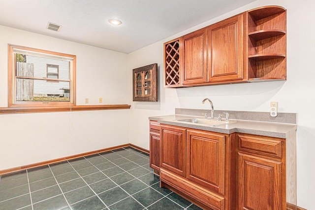 kitchen with baseboards, visible vents, open shelves, a sink, and brown cabinets