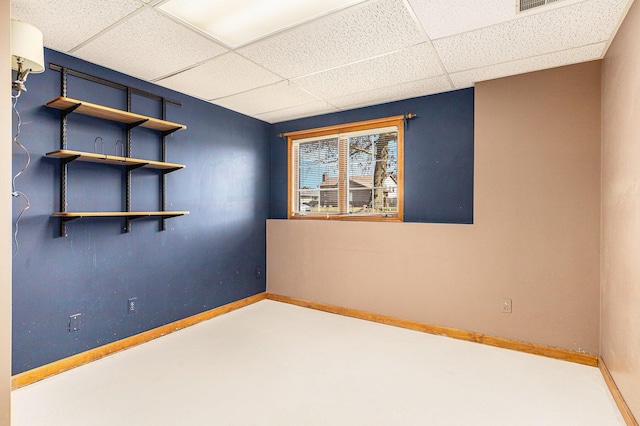 empty room with visible vents, a paneled ceiling, and baseboards