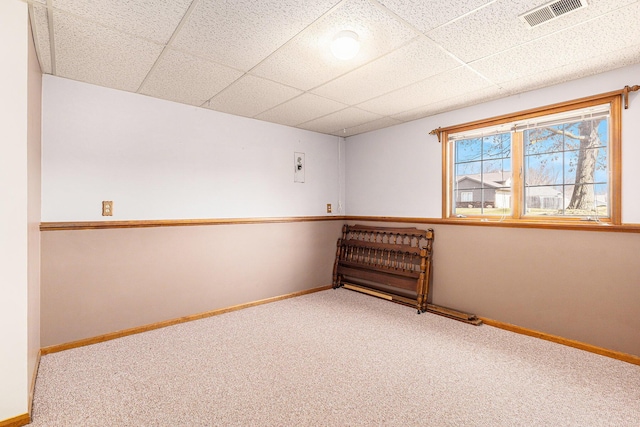 carpeted empty room with baseboards, visible vents, and a paneled ceiling