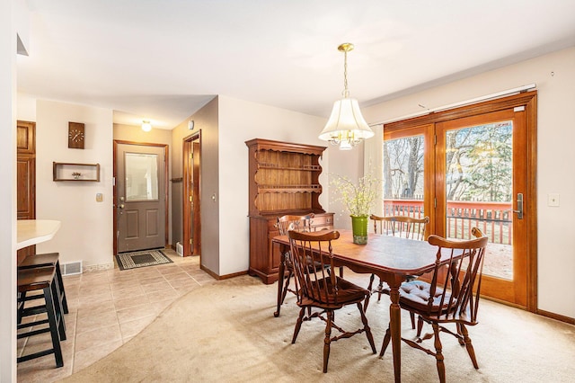 dining space with light colored carpet, an inviting chandelier, baseboards, and visible vents