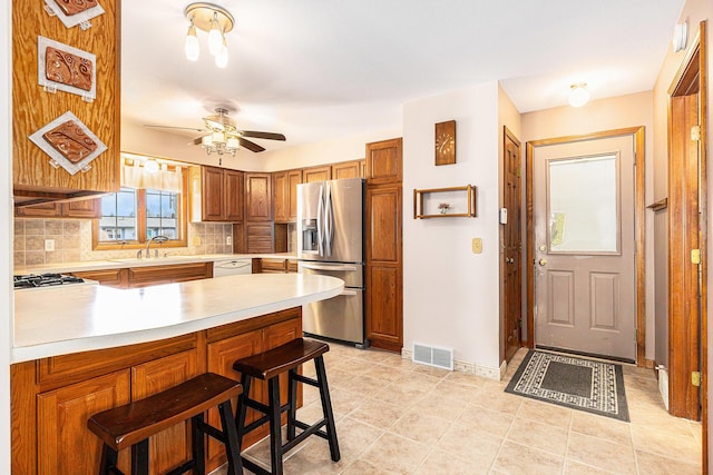 kitchen with visible vents, a peninsula, light countertops, dishwasher, and stainless steel fridge