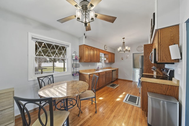 kitchen with brown cabinets, light wood finished floors, a sink, appliances with stainless steel finishes, and light countertops