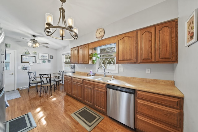 kitchen with brown cabinetry, a sink, light countertops, and stainless steel dishwasher