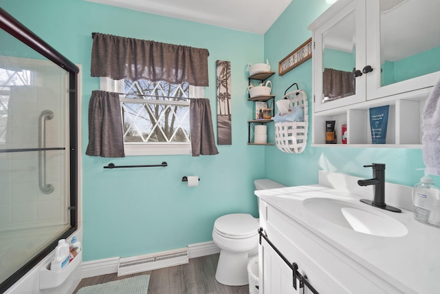 full bath featuring toilet, wood finished floors, shower / bath combination with glass door, baseboards, and vanity