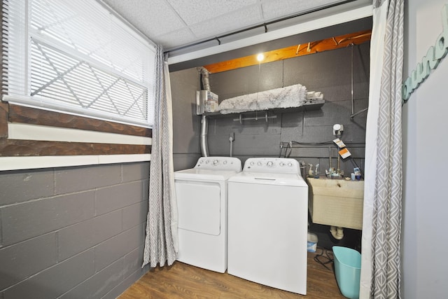 clothes washing area with washer and dryer, a sink, wood finished floors, concrete block wall, and laundry area