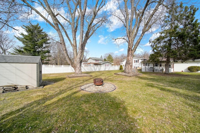 view of yard featuring a shed, an outdoor fire pit, an outdoor structure, and fence